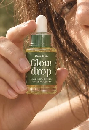 A hand holding the Glow Drop bottle